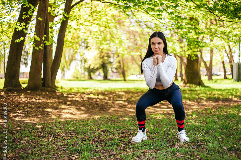 Girl stretches, prepares her body and muscles for a productive fitness workout. Flexible female sporty model in the city park. Image with copy space. Girl stretches, prepares her body and muscles for a productive fitness workout. Flexible female sporty model in the city park. Image with copy space.