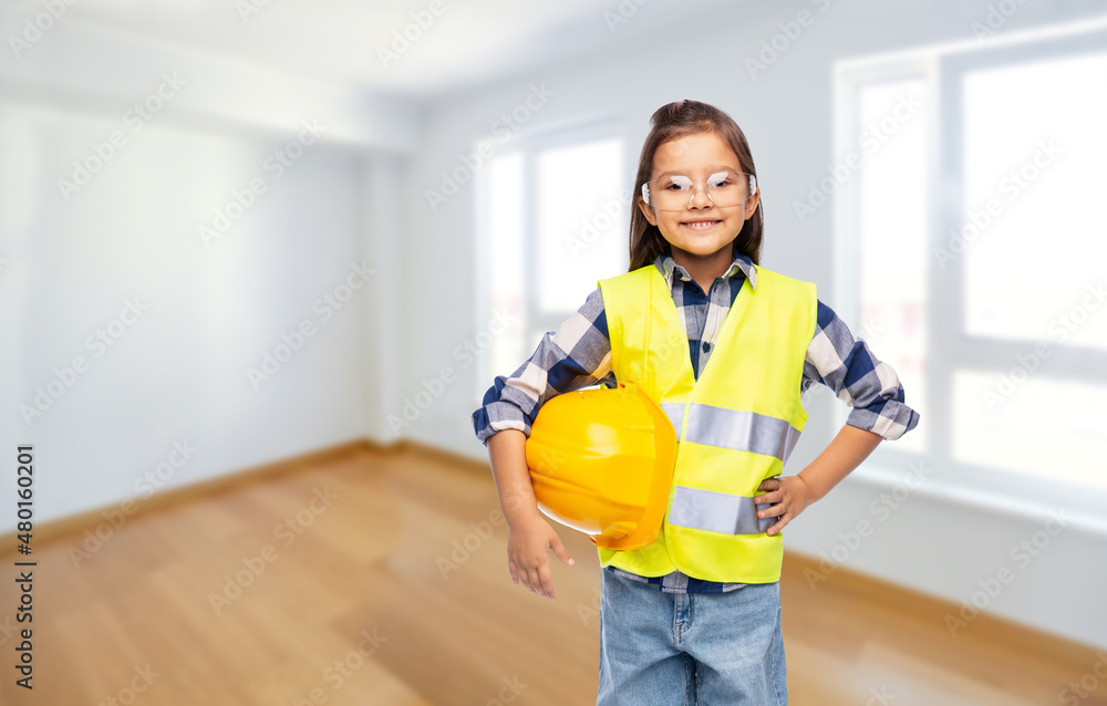 building, construction and profession concept - smiling little girl with protective helmet in safety vest and goggles over empty room background building, construction and profession concept - smiling little girl with protective helmet in safety vest and goggles over empty room background