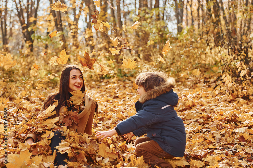 Beautiful nature. Mother with her son is having fun outdoors in the autumn forest Beautiful nature. Mother with her son is having fun outdoors in the autumn forest