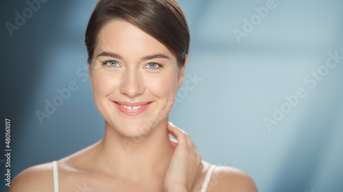Female Beauty Portrait. Beautiful Caucasian Woman with Brown Hair and Light Green Eyes Posing, Touching Her Natural, Healthy Skin. Wellness and Skincare Concept on Soft Isolated Background. Close Up.