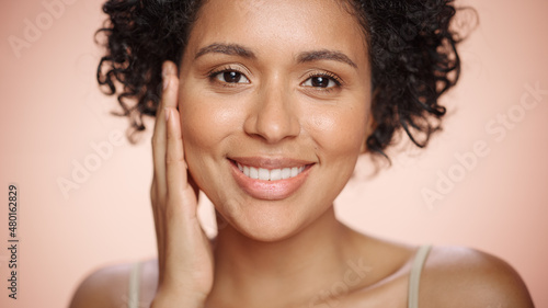 Female Beauty Portrait. Beautiful Black Multiethnic Latina Woman with Afro Hair Posing  Touching Her Natural  Healthy Skin. Wellness and Skincare Concept on Soft Isolated Background. Close Up.