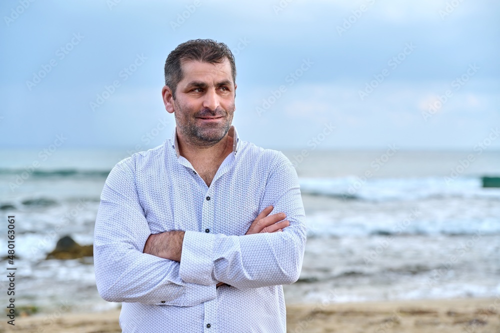 Portrait of confident mature man with crossed arms, sky sea copy space Portrait of confident mature man with crossed arms, sky sea copy space