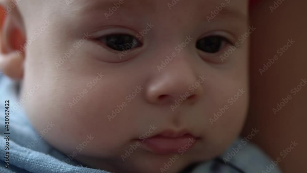 Close-up Cute Face Of Newborn Baby In Early Days Wakes Up And Opens Eyes. Infant Child Grimaces After Dream In Blue Bodysuit. Kid In First Minutes Of Life Portrait In Macro. Childhood, Infancy Concept Close-up Cute Face Of Newborn Baby In Early Days Wakes Up And Opens Eyes. Infant Child Grimaces After Dream In Blue Bodysuit. Kid In First Minutes Of Life Portrait In Macro. Childhood, Infancy Concept