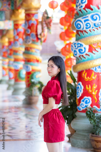 Portrait beautiful smiles Asian young woman wearing red cheongsam dress traditional decoration for Chinese new year festival celebrate culture of china at Chinese shrine Public places in Thailand