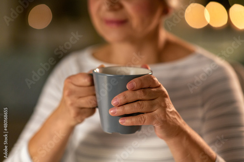 drinks and people concept - close up of senior woman with cup of tea at home