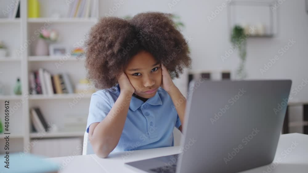 Portrait of little girl sitting in front of laptop, tired of exhaustive studying Portrait of little girl sitting in front of laptop, tired of exhaustive studying