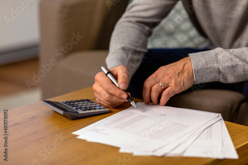 savings, annuity insurance and people concept - close up of senior man with papers or bills and calculator writing at home in evening photo
