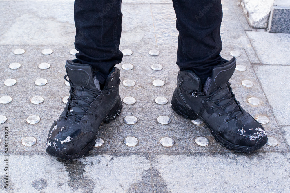feet in black boots stand on the anti-slip surface of the tile