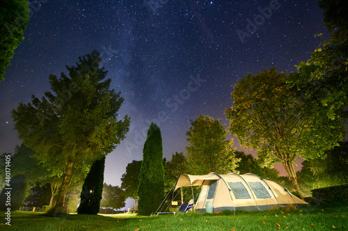 A camping tent surrounded by green trees under the starry sky in luxembourg