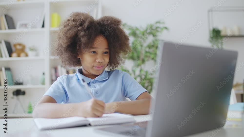 Cute African American schoolgirl having online video lesson on laptop at home Cute African American schoolgirl having online video lesson on laptop at home