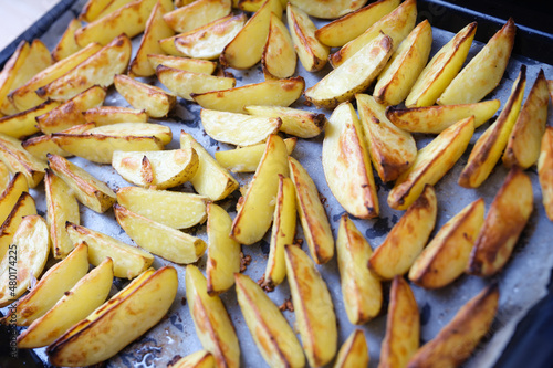 Homemade baked potato wedges on a parchment baking sheet
