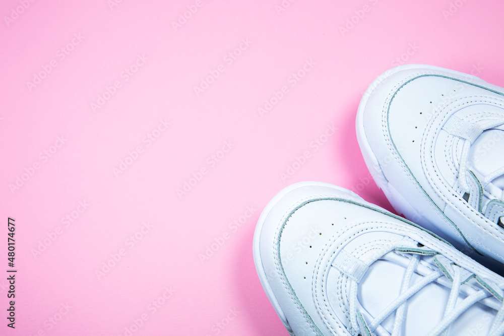 Modern sneakers on the pink background. White leather trainers on big sole with spikes. Close up. Modern sneakers on the pink background. White leather trainers on big sole with spikes. Close up.