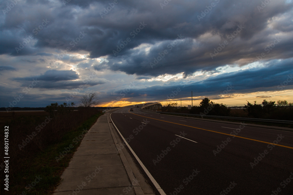 Empty asphalt road at sunset with clouds.