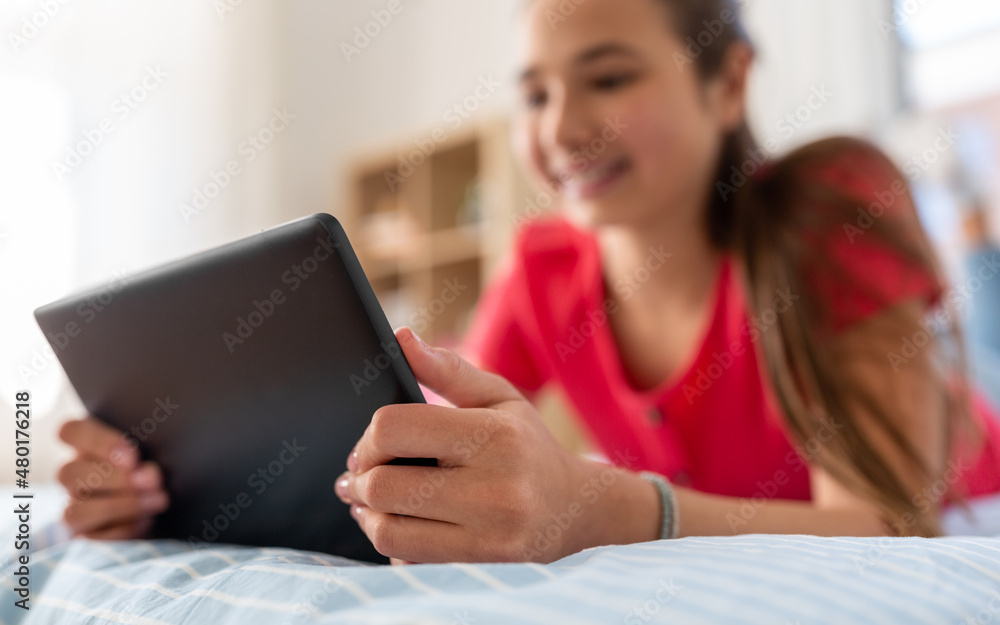 technology and communication concept - close up of smiling teenage girl with tablet computer lying on bed at home technology and communication concept - close up of smiling teenage girl with tablet computer lying on bed at home
