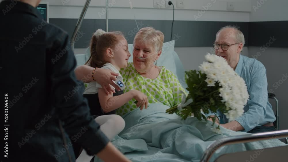 Old patient receiving visit from child and mother in hospital ward. Kid with flowers running to hug sick woman in bed, visiting grandma to give comfort and help with recovery. Family at clinic Old patient receiving visit from child and mother in hospital ward. Kid with flowers running to hug sick woman in bed, visiting grandma to give comfort and help with recovery. Family at clinic