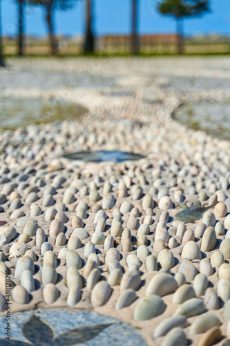 Fototapeta Naklejka Na Ścianę i Meble -  A trail made of small stones for foot massage on the promenade by the sea