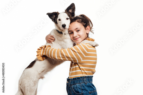 A young girl looking at the camera with her mongrel dog. Love between owner and dog. Isolated on white background. Studio portrait. Horizontal photography