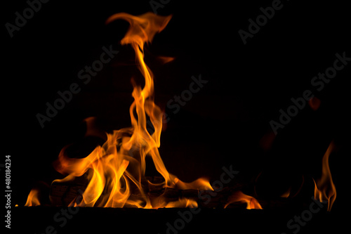 Bright orange bonfire flame on a black background. Abstract fiery texture. Realistic flame of fire burns the motion frame. Texture for design. The texture of fire. A blazing burning bonfire.