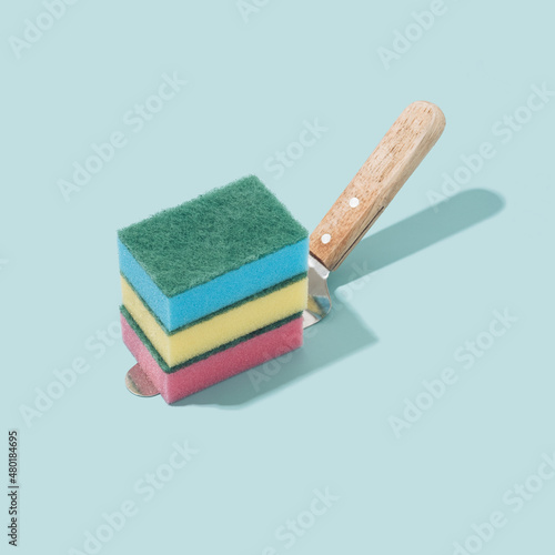 Colorful sponges on a cake spatula and pastel blue background. Immersive reality fantasy concept.