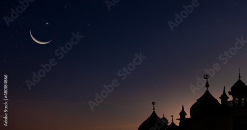 Silhouette dome mosques and crescent moon on dark blue dusk sky background free space for text Arabic with religious Islamic Ramadan Kareem or Muharram new year