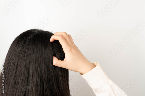 Woman scratching her head because of an itchy scalp. Causes of itchy includes dandruff, seborrheic dermatitis, psoriasis, Tinea capitis or allergy to hair care products.