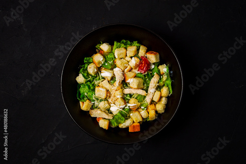 Fresh traditional Caesar salad, with chicken, on a black background,Top view, dark background, horizontal no people,