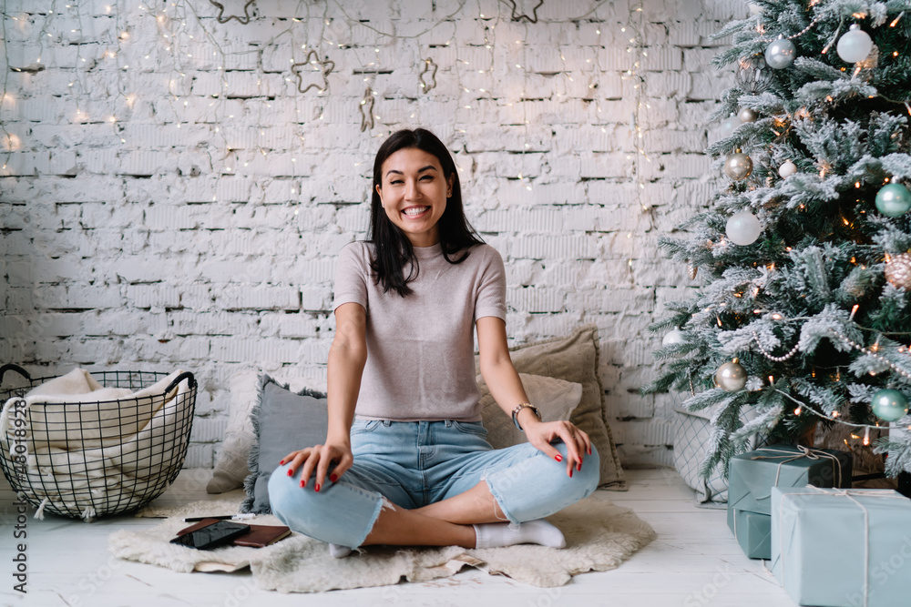Chinese girl sitting near Christmas tree at home Chinese girl sitting near Christmas tree at home