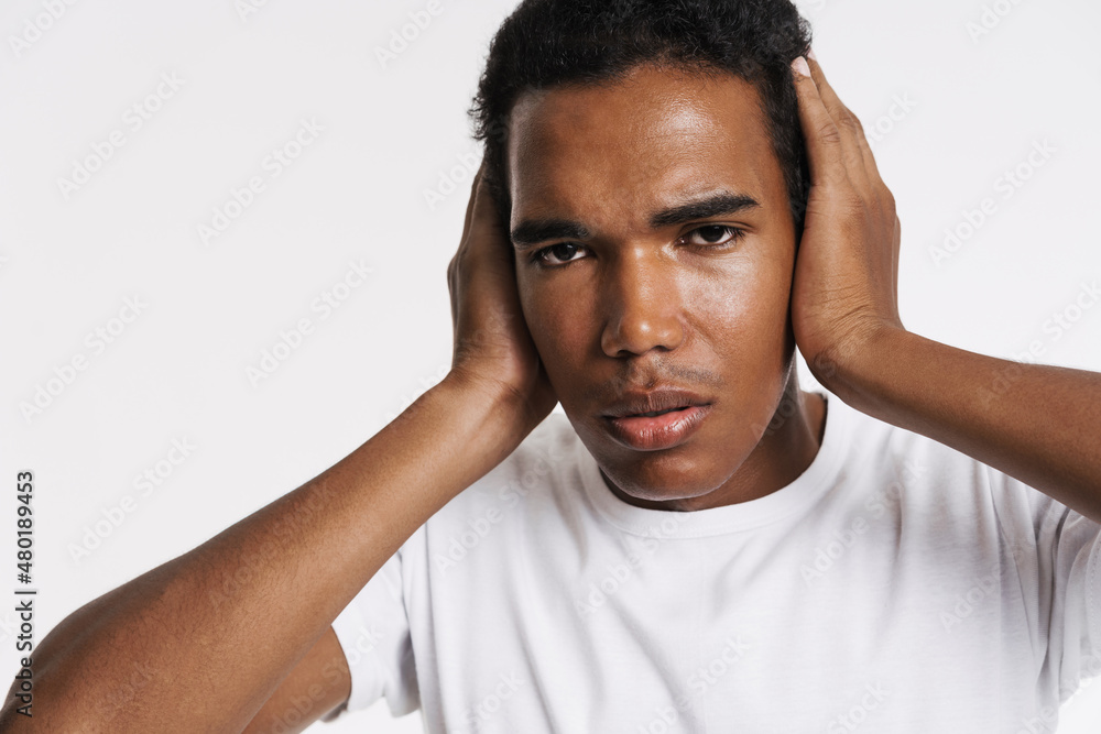 Young black man looking at camera while covering his ears Young black man looking at camera while covering his ears