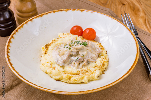 Stroganoff with mashed potatoes on white plate on wooden table