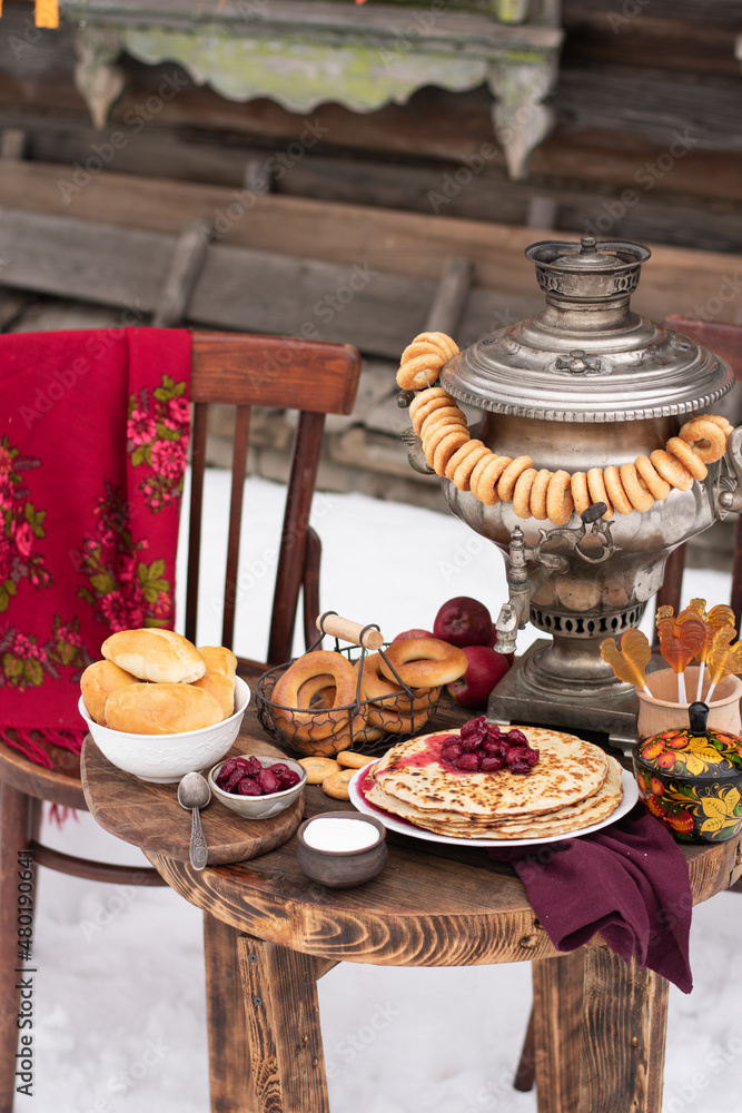 Festive decor for Maslenitsa on the table: pancakes, bagels, a samovar. Russian folk traditions. Shrovetide concept.