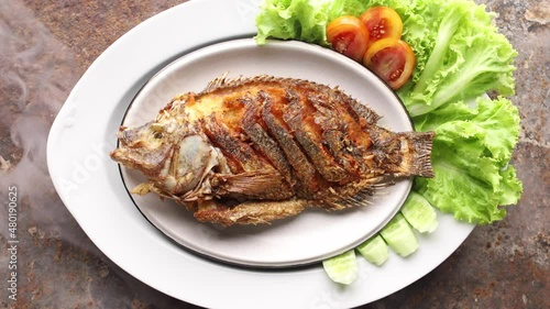 fried nile tilapia fish with lettuce, tomato and cucumber in ceramic plate on rusty texture background, top view, 3840 x 2160, 4K