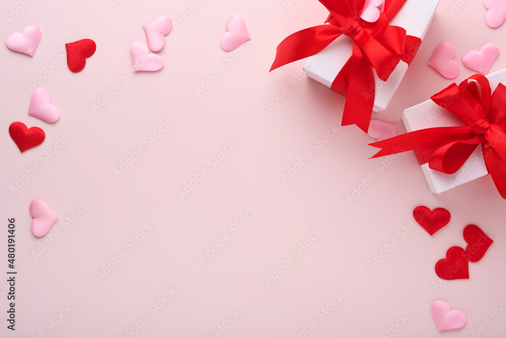 White gift boxes with red ribbon and small red decorative hearts on pink background. Top view with copy space. Valentines day or Wedding romantic concept. Festive composition. Mock up.