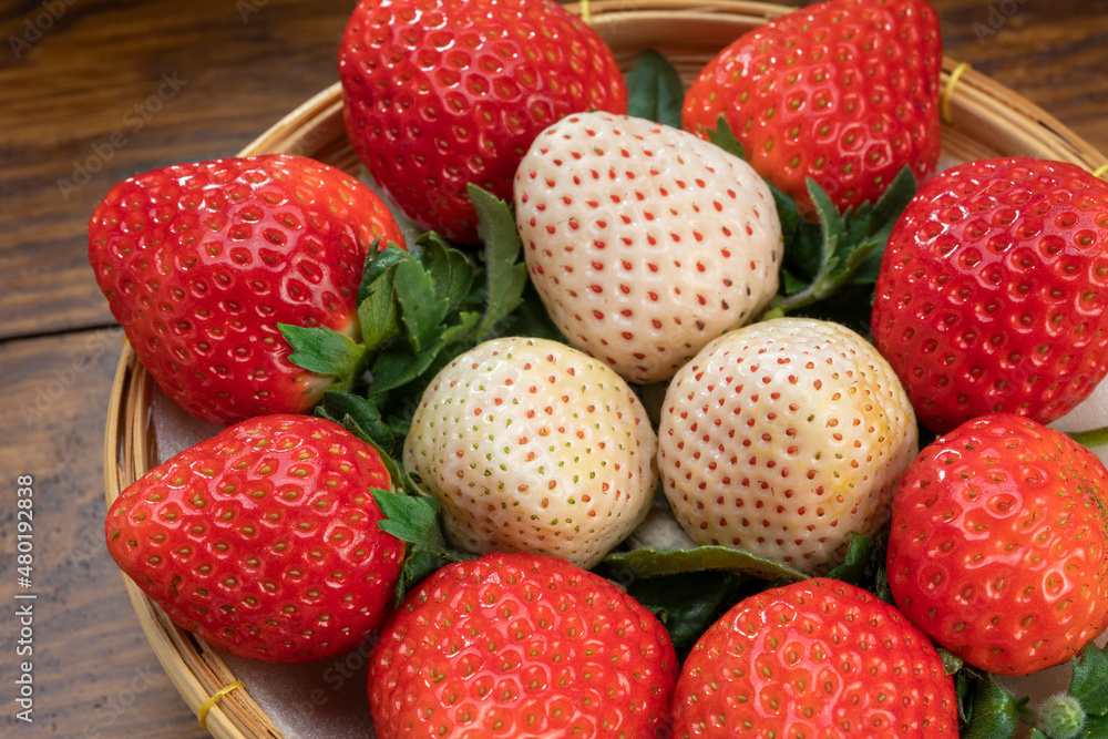Fresh red and white strawberries in a wooden basket on wooden background, Red Strawberry and Pine berry or Hula strawberry in Bamboo basket. Fresh red and white strawberries in a wooden basket on wooden background, Red Strawberry and Pine berry or Hula strawberry in Bamboo basket.