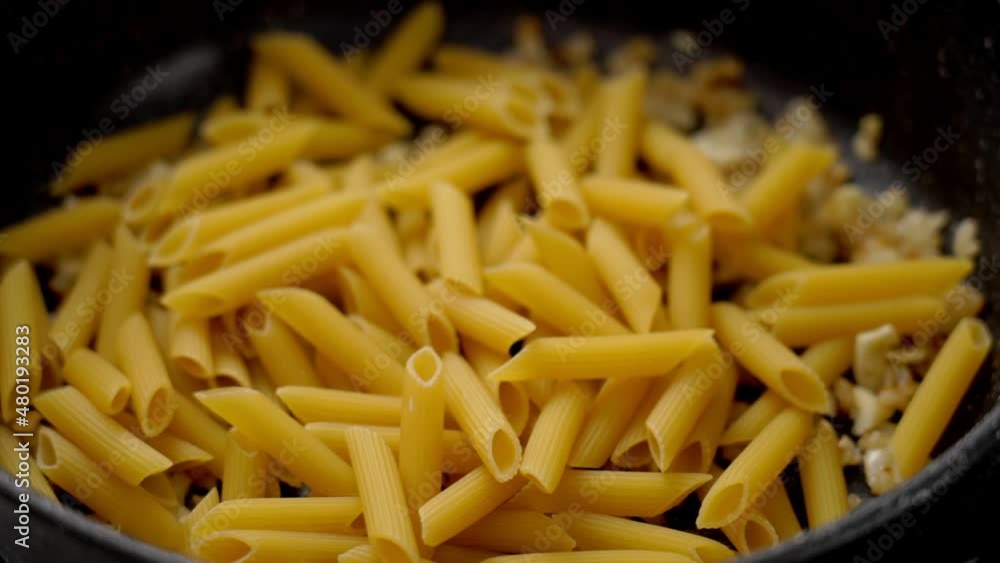 Person cooking pasta on frying pan Person cooking pasta on frying pan