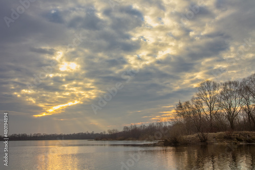 spring landscape. sun shining through heavy clouds over the lake