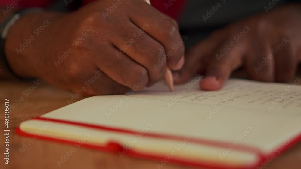 African man writing something in notepad in office at night African man writing something in notepad in office at night