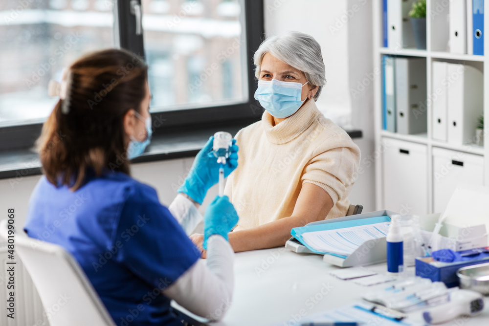 medicine, health and vaccination concept - doctor or nurse filling syringe with vaccine or drug and senior woman in mask at hospital medicine, health and vaccination concept - doctor or nurse filling syringe with vaccine or drug and senior woman in mask at hospital