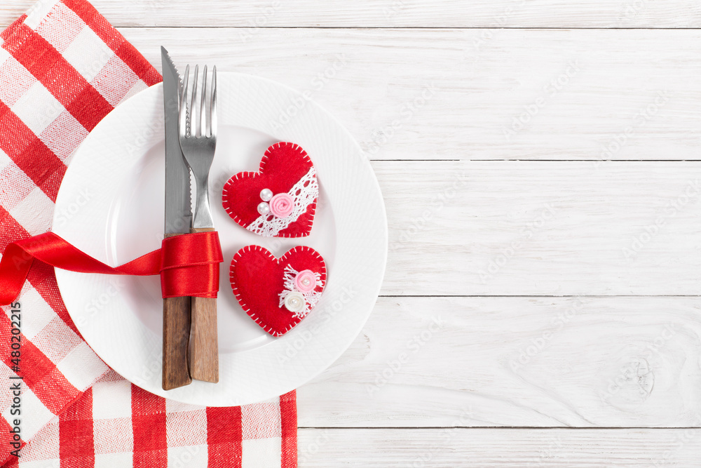 Valentine handmade fabric hearts in plate for romantic dinner flat lay with copy-space background on white wooden table