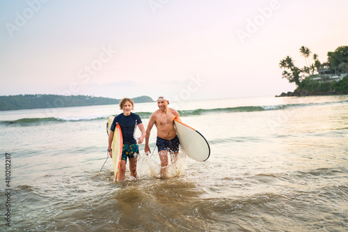 Photography Portrait of a teen boy with his father with surfboards after surfing