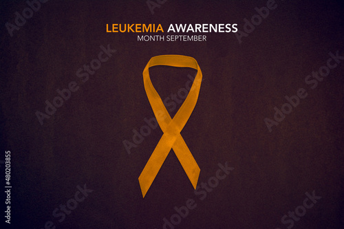 Leukemia Awareness Month. Orange Color Ribbon on brown background.