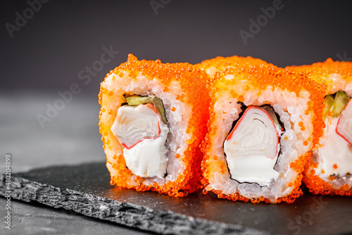 appetizing sushi roll california with cheese cucumber crab and masago caviar on a black stone plate photo