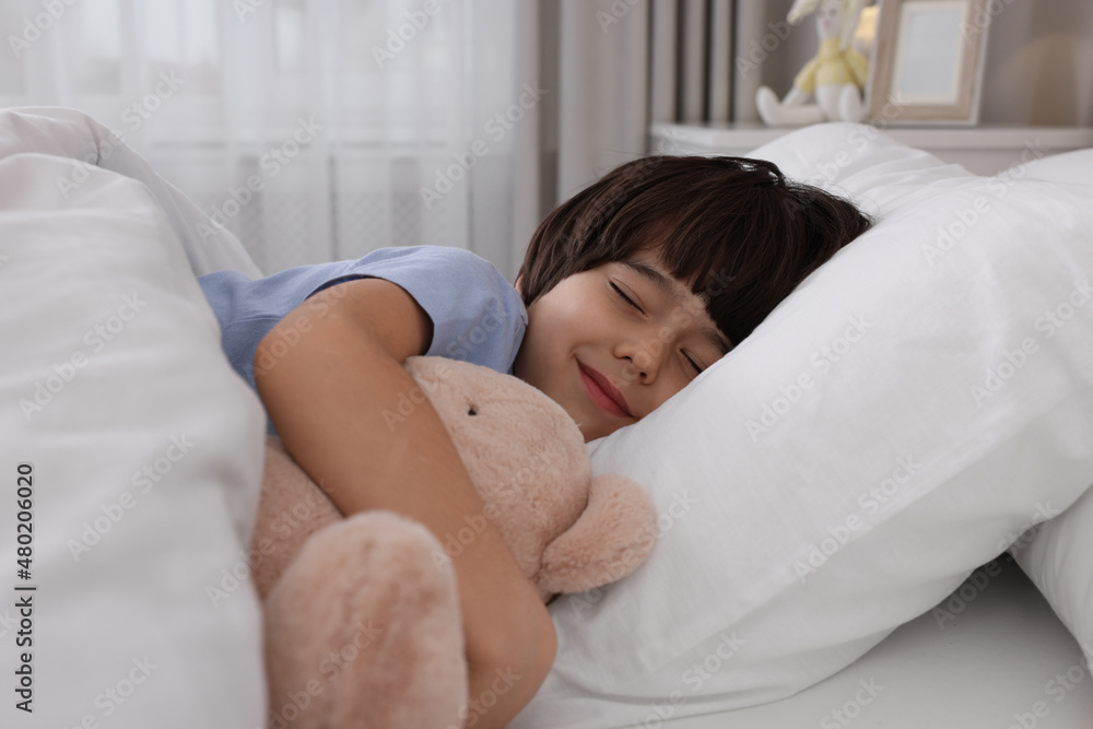 Cute little boy with toy bear sleeping in bed at home Cute little boy with toy bear sleeping in bed at home