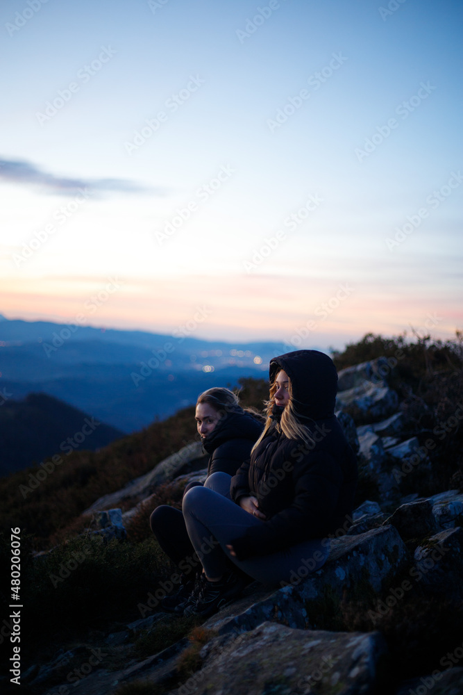 Friends enjoying a sunset on top of a mountain with their dog