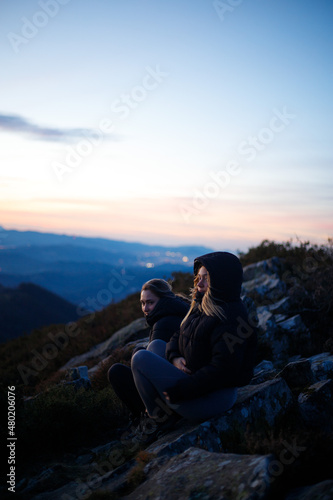 Friends enjoying a sunset on top of a mountain with their dog