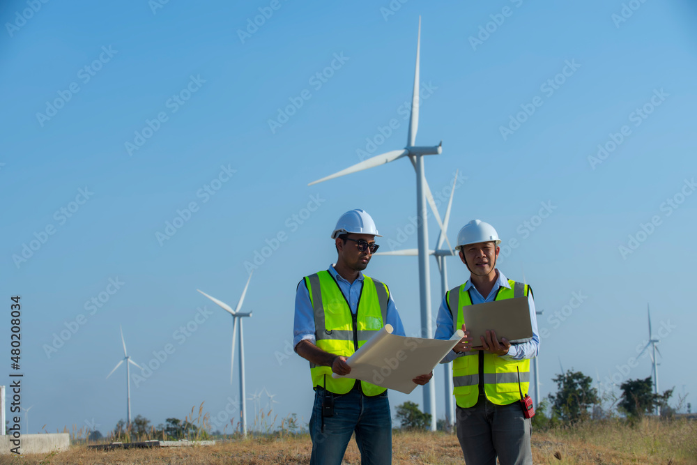 engineer with turbine. Two engineers working and holding wind measurement on wind turbine farm Power Generator Station on mountain, Thailand people engineer with turbine. Two engineers working and holding wind measurement on wind turbine farm Power Generator Station on mountain, Thailand people