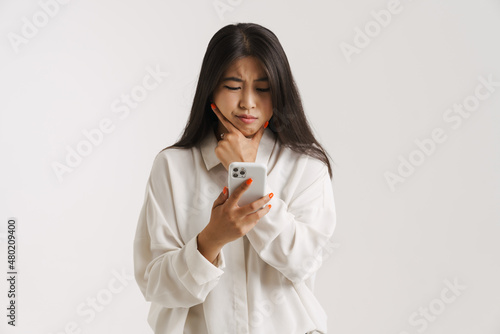 Fototapeta Young asian woman frowning while using mobile phone