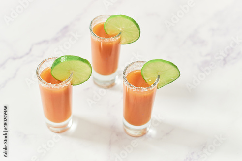 Three tequila shots with sangrita and lime on top. Mexican appetizer for tequila. photo