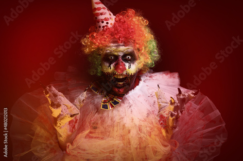 Fototapeta Naklejka Na Ścianę i Meble -  Terrifying clown on dark background. Halloween party costume