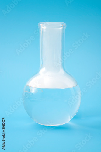 Science laboratory, scientific experiment and lab test concept with dry ice in a glass chemistry beaker isolated on blue background