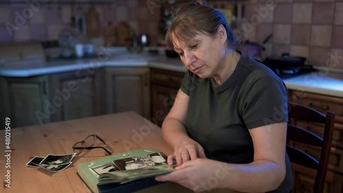 Middle aged woman looking at family photo album. Nostalgia, happines and memories at middle age concept.